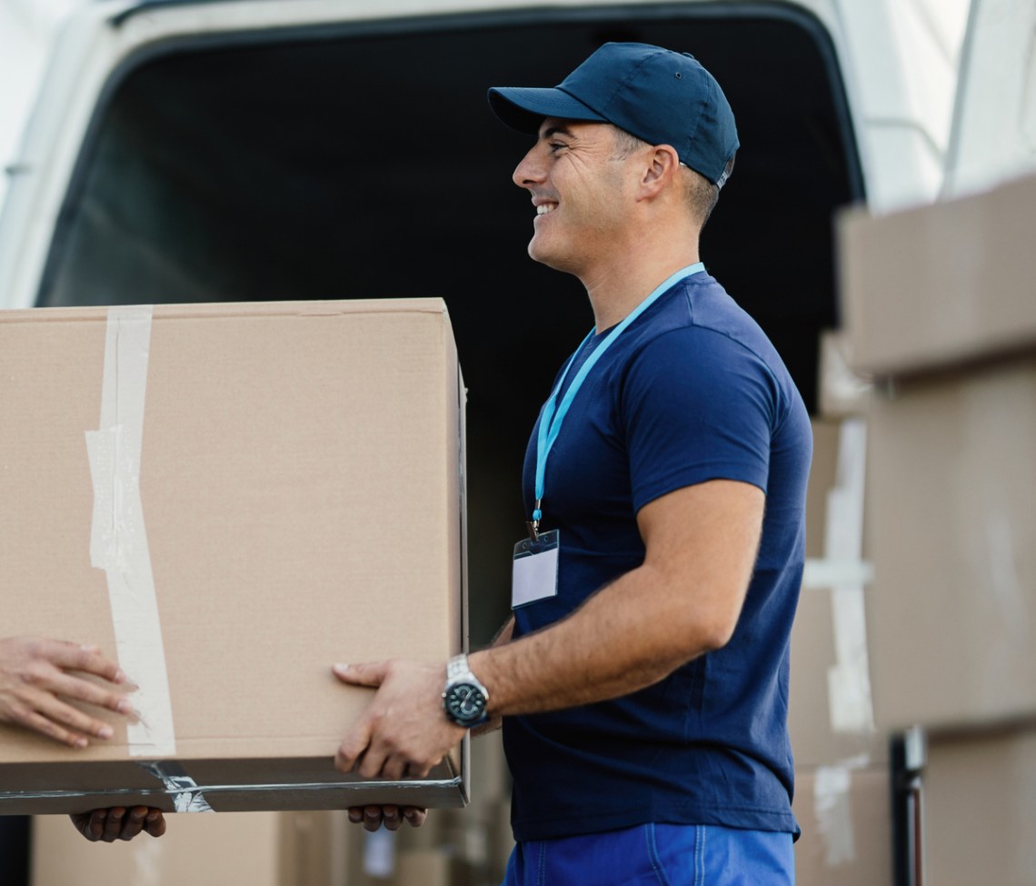 happy delivery men unloading cardboard box from a mini van.